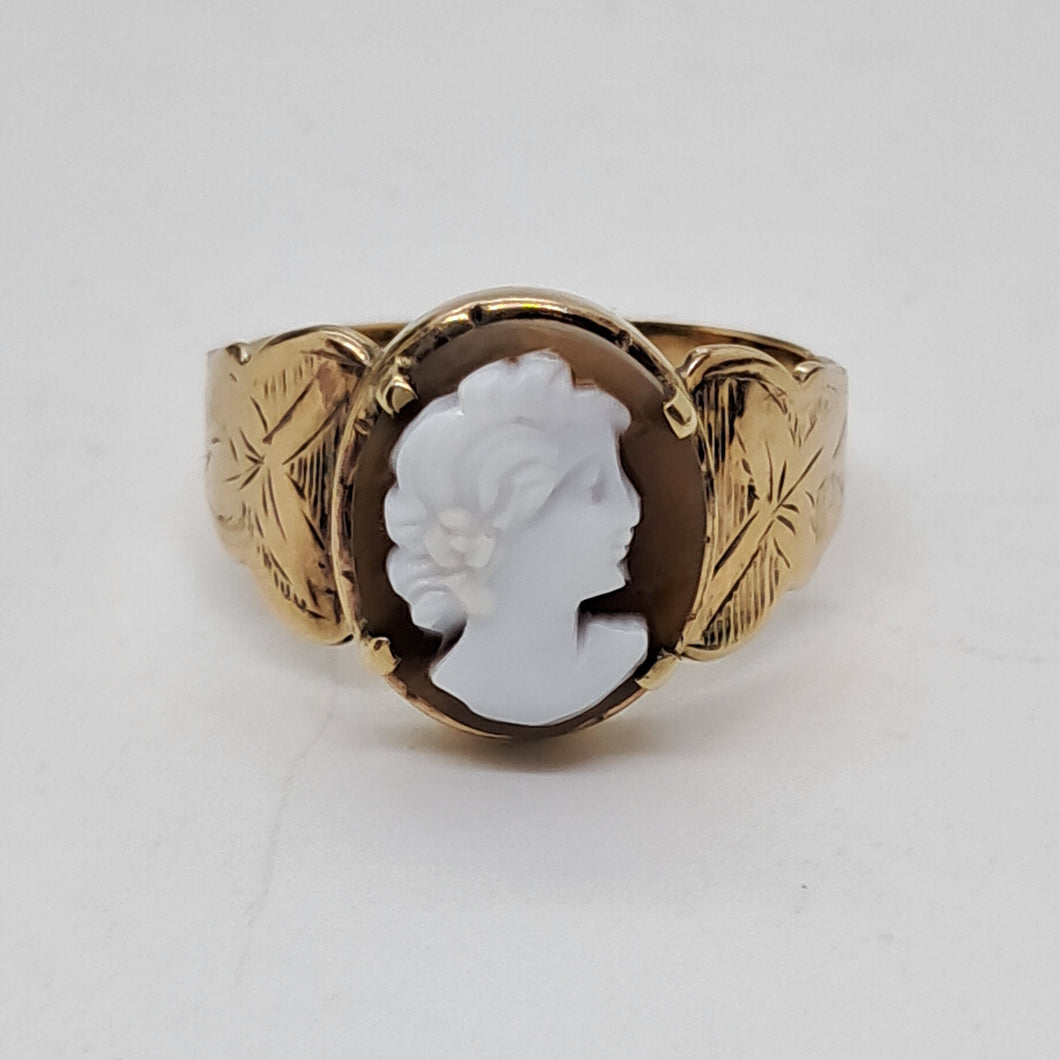 Gold ring with a white cameo on a light gray background